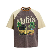 A short-sleeve raglan t-shirt with a washed dark brown body and light beige sleeves. The front features a graphic print of a vintage 'Mafa's' sign with palm trees and a sunset.