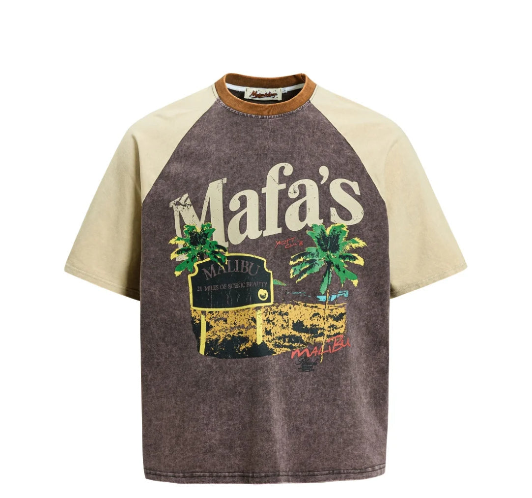 A short-sleeve raglan t-shirt with a washed dark brown body and light beige sleeves. The front features a graphic print of a vintage 'Mafa's' sign with palm trees and a sunset.
