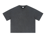 A dark grey short-sleeve t-shirt with a washed, vintage texture, featuring a crew neck with small silver studs. 