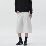 Person wearing a black sweatshirt, white wide-leg pants, and black sneakers on a light gray background