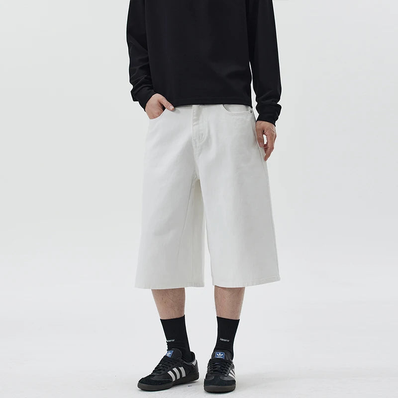 Person wearing a black sweatshirt, white wide-leg pants, and black sneakers on a light gray background