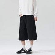 Person wearing black wide-leg pants and white sneakers on a plain background