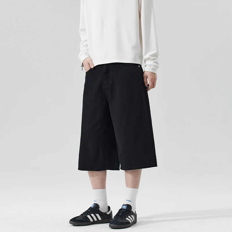 Person wearing black wide-leg pants and white sneakers on a plain background