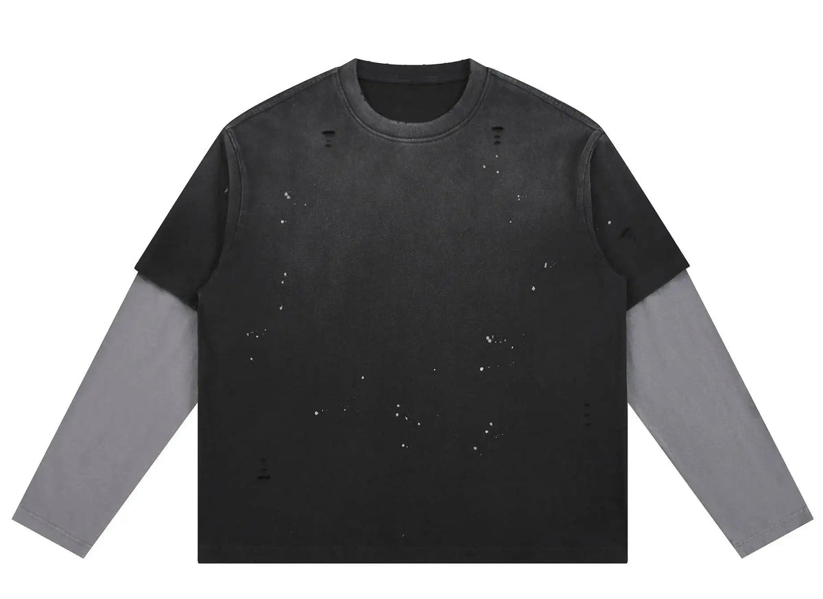A long-sleeve distressed crewneck shirt with a black body and faded gray sleeves, featuring small white speckled details across the front, shown on a plain white background.