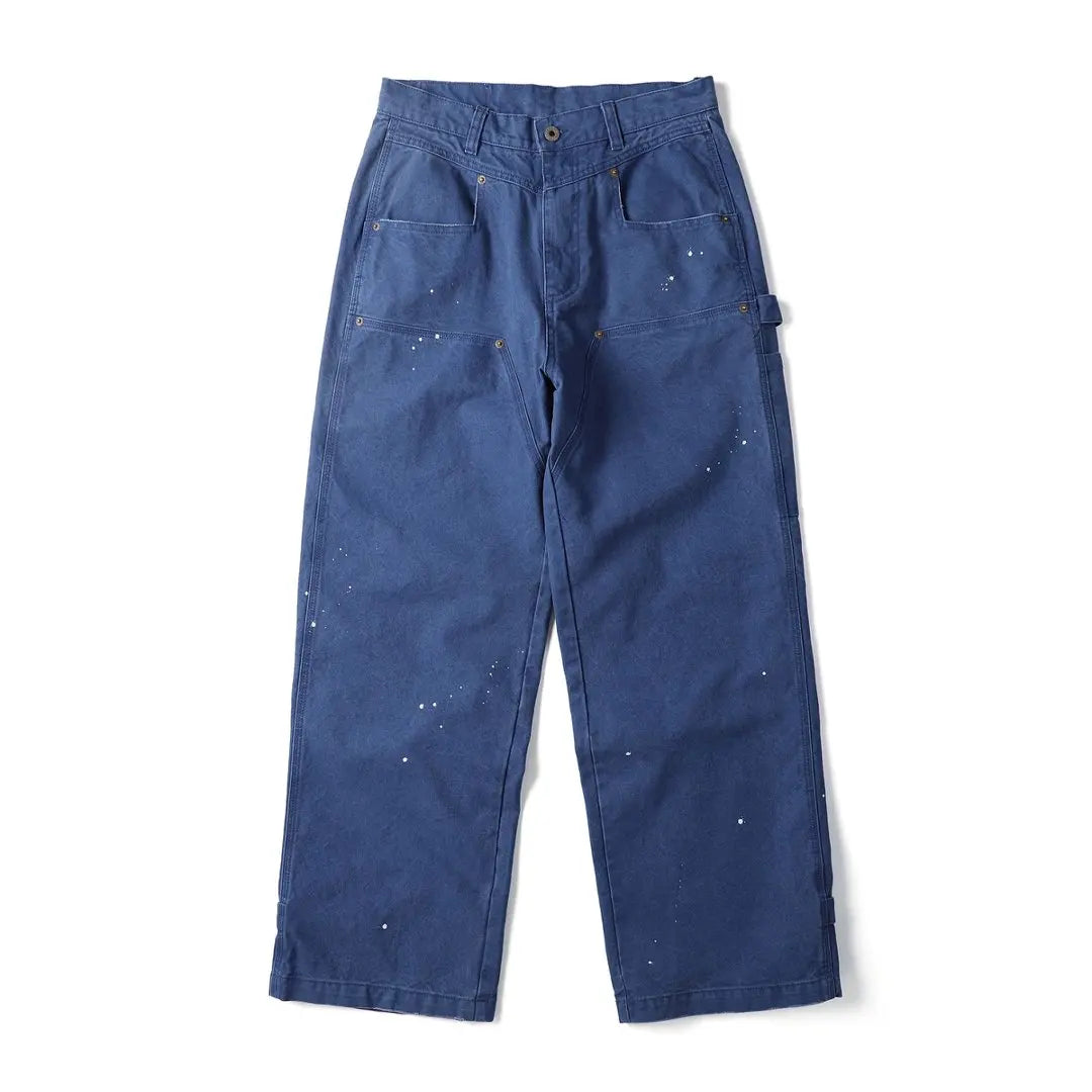 A pair of dark blue canvas work pants with white paint splatters, shown flat against a white background.