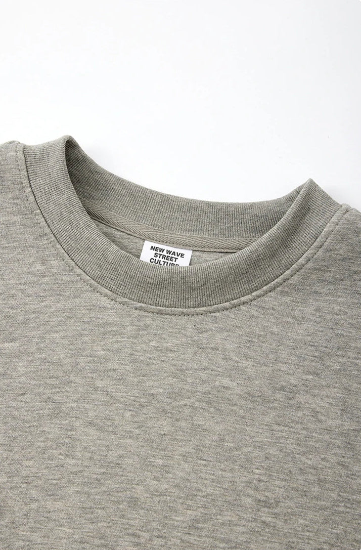 Close-up of a light gray heather crewneck sweatshirt showing the ribbed collar and inner neck label, with Chinese and English text at the bottom describing the collar features.