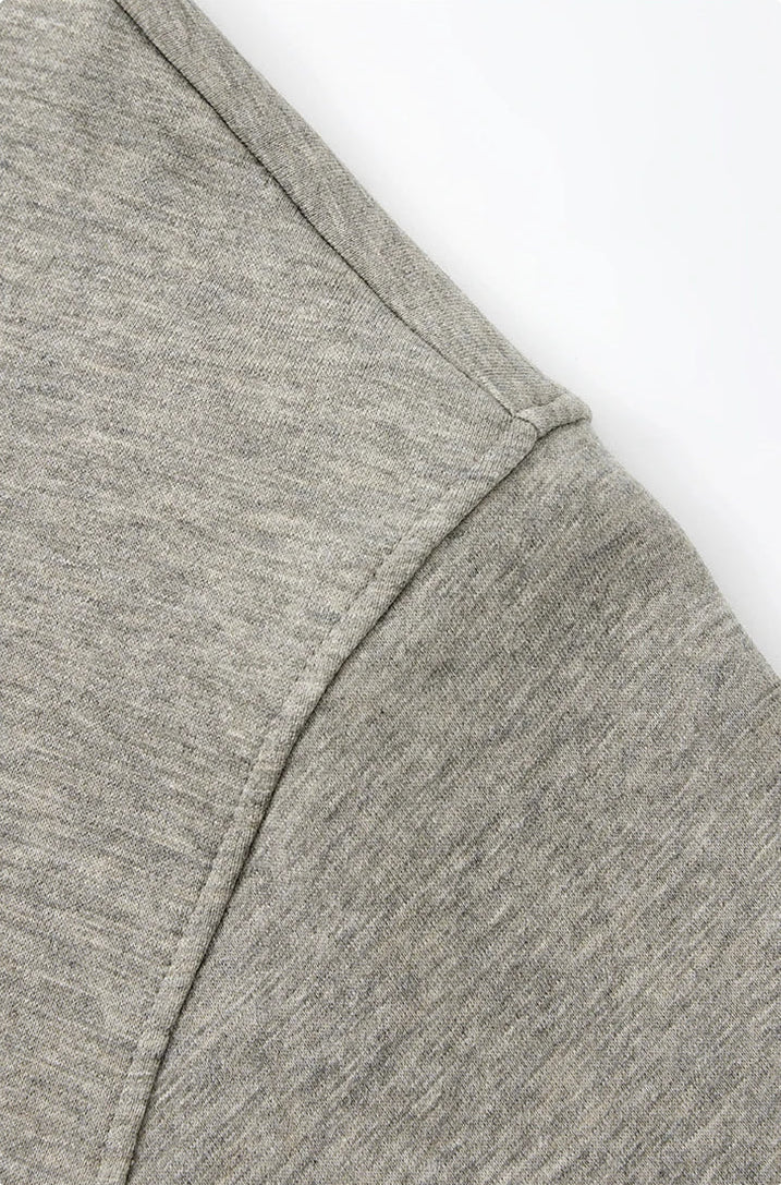 Close-up of a heather gray fabric garment detail with a clean seam and a line of Chinese text below on a white background.