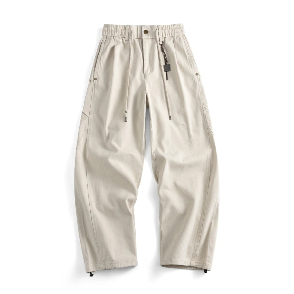 A pair of light beige wide-leg pants with an elastic waistband, drawstring, and zippered side pockets, shown flat on a white background.