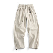 A pair of light beige wide-leg pants with an elastic waistband, drawstring, and zippered side pockets, shown flat on a white background.