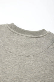 Close-up detail shot of a light gray heather crewneck sweatshirt, showing the curved reinforced back panel and collar stitching, with Chinese and English text at the bottom describing the feature.