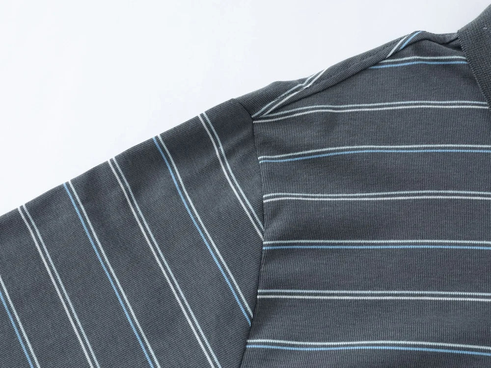 Close-up of a dark gray striped shirt fabric with thin white and light blue pinstripes, showing the shoulder seam and collar area.