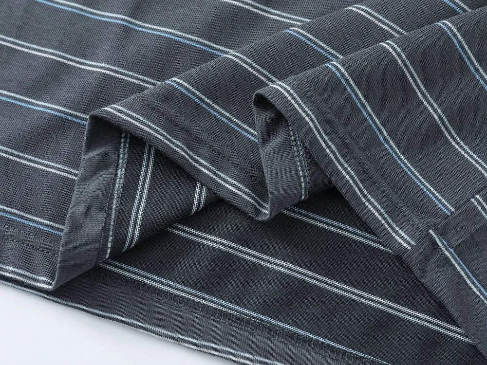 Close-up of a dark gray striped fabric with thin white and light blue pinstripes, folded to show the texture and stitching.